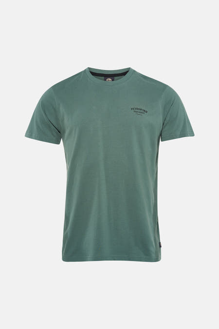 T-shirt vert à manches courtes de Petrol Industries, avec texte imprimé au dos, combiné avec un jean bleu et des chaussures blanches.