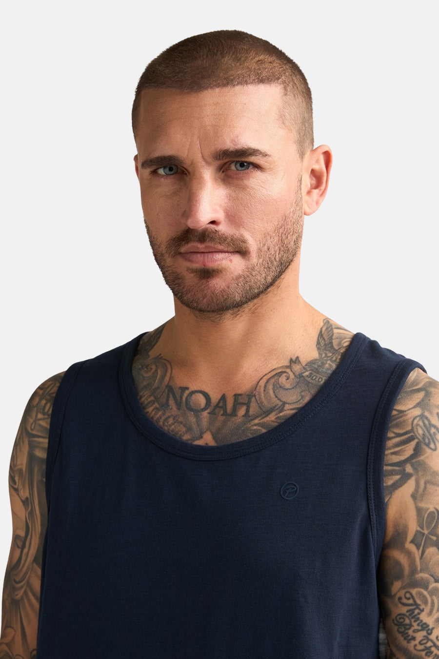 Blauwe singlet van Petrol Industries, gedragen door een man met tatoeages op borst en armen.
