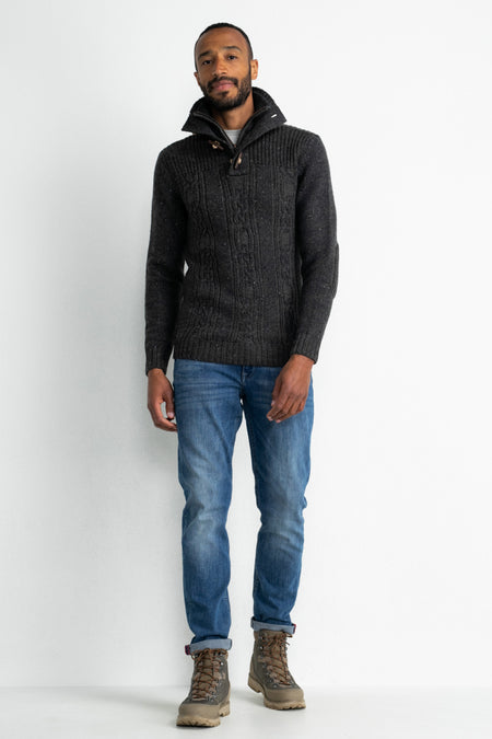 Pull gris de Petrol Industries®, avec motif torsadé et col montant, combiné avec un jean et des bottes.