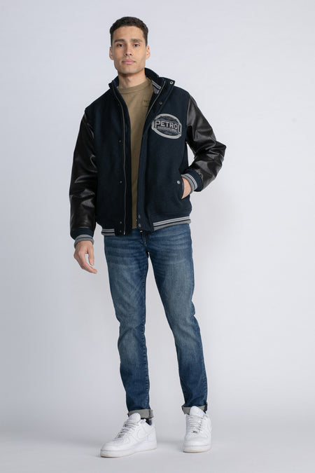 Jean bleu de Petrol Industries, avec des manches en cuir, un logo brodé et des jeans décontractés et des baskets blanches.