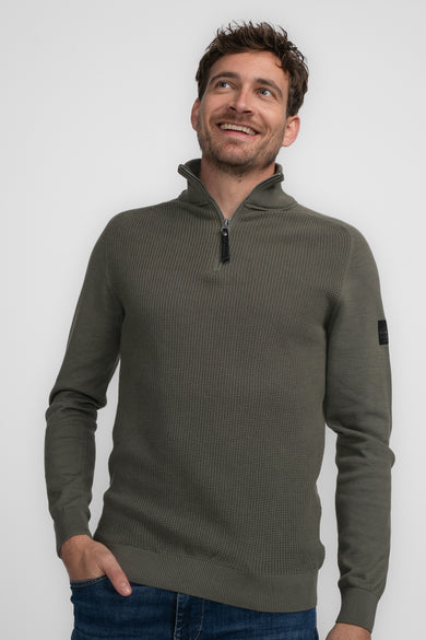 Khaki trui met rolkraag van Petrol Industries®, met een rits en lange mouwen, gecombineerd met jeans.