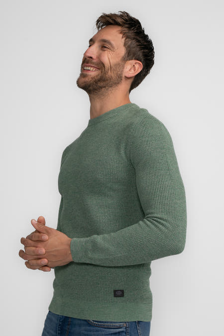 Groene trui met ronde hals van Petrol Industries®, in wafelstructuur en gedragen met een jeansbroek.
