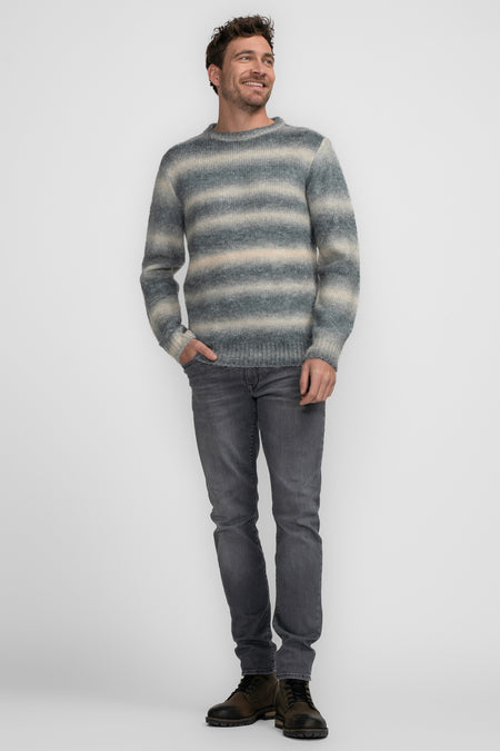 Blauwe trui met ronde hals van Petrol Industries®, gestreept patroon, gecombineerd met grijze jeans en bruine laarzen.