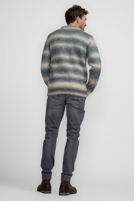 Blauwe ronde hals trui van Petrol Industries, met horizontale strepen en grijze jeans en bruine laarzen.
