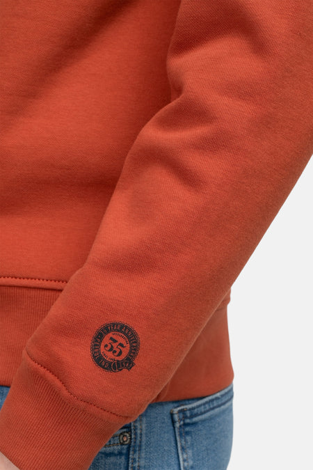 Rode sweater van Petrol Industries, met lange mouwen en een ronde 55 jaar jubileum badge op de mouw.
