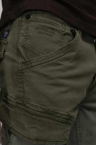 Pantalon de travail vert de Petrol Industries avec des poches et un vêtement marron au-dessus du pantalon.