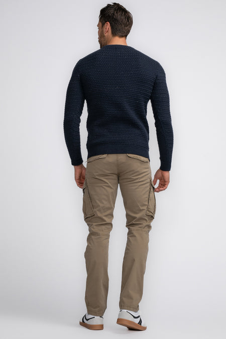 Bruine cargobroek van Petrol Industries®, achterzijde met grote zijzakken, gedragen met donkerblauwe trui en witte sneakers.