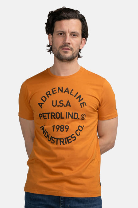 T-shirt orange à manches courtes de Petrol Industries, vu de derrière, associé à des jeans foncés et des baskets blanches.