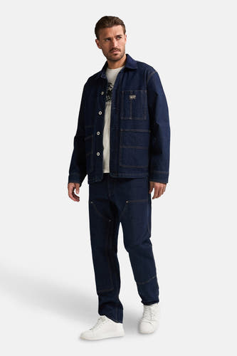 Blauwe jeansjas van Petrol Industries® met knoopsluiting en opgestikte zakken, gedragen met een wit T-shirt en donkere jeans.
