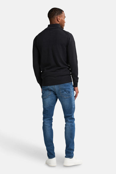 Zwart gilet van Petrol Industries, gezien van achteren, gecombineerd met een blauwe jeans en witte sneakers.
