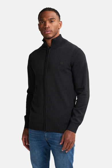 Zwart gilet van Petrol Industries met een ritssluiting en ribgebreide kraag, gedragen met een blauwe jeans.
