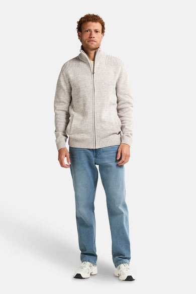Gilet écru de Petrol Industries avec une fermeture à glissière et des poches, associé à un jean et des baskets blanches.