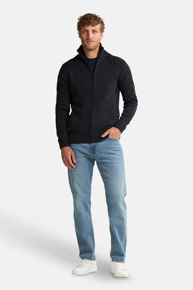 Zwart gilet van Petrol Industries®, gedragen met een blauw shirt en jeans, witte sneakers.