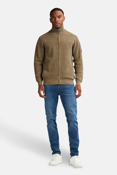 Beige gilet van Petrol Industries, met een ritssluiting en gedragen met een blauwe jeans en witte sneakers.
