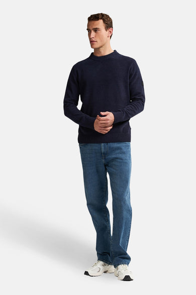 Blauwe trui met ronde hals van Petrol Industries®, gedragen met jeans en witte sneakers.