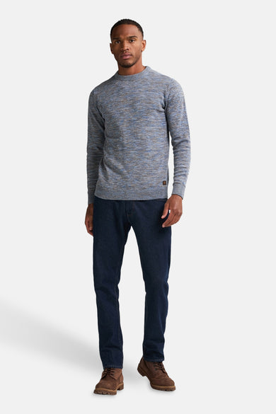 Blauwe trui met ronde hals van Petrol Industries®, met lange mouwen, gecombineerd met donkere jeans en bruine schoenen.
