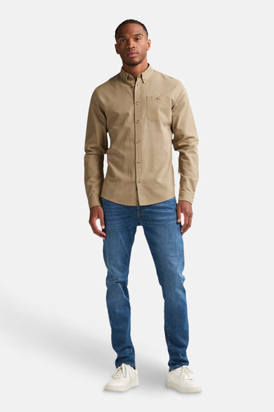 Chemise beige à longues manches de Petrol Industries, associée à des jeans et des baskets blanches.