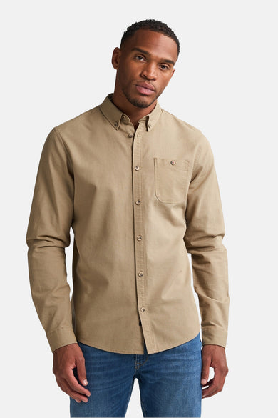Chemise homme beige à longues manches de Petrol Industries, avec poche poitrine et portée avec des jeans.