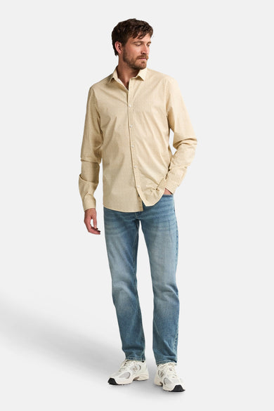 Beige overhemd met lange mouwen van Petrol Industries, gedragen met blauwe jeans en witte sneakers.