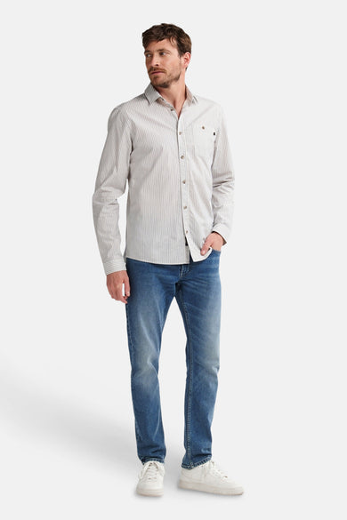 Blauw overhemd met lange mouwen van Petrol Industries, met een fijn streepjespatroon, gedragen met jeans en witte sneakers.
