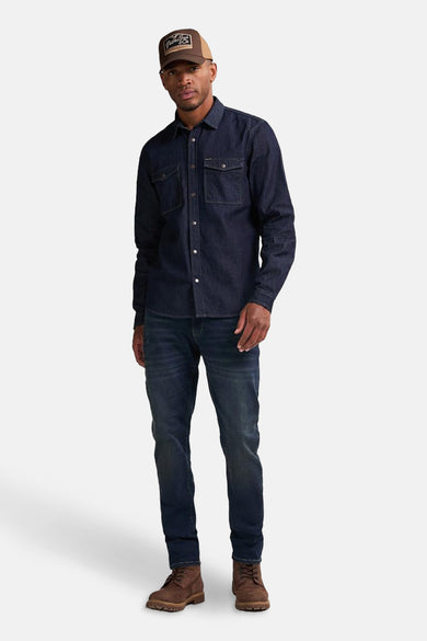 Donkerblauw denim overhemd met lange mouwen van Petrol Industries®, compleet met jeans en bruine schoenen.
