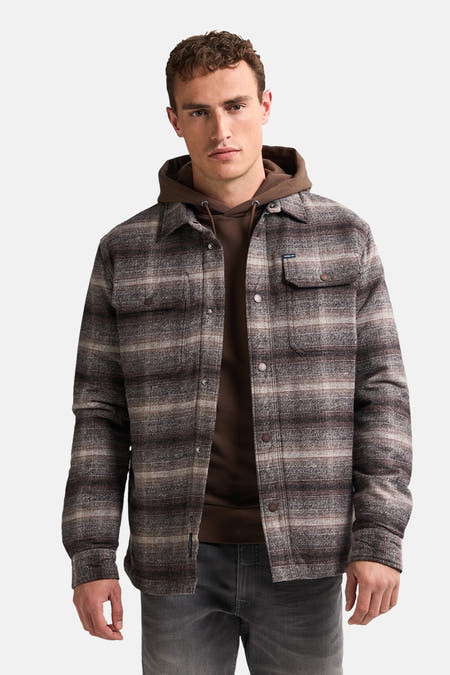 Bruine korte jas van Petrol Industries met een geruit patroon, over een bruine hoodie.
