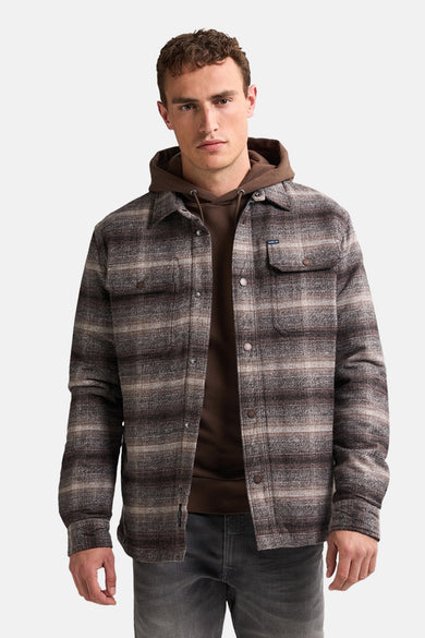 Bruine korte jas van Petrol Industries met een geruit patroon, over een bruine hoodie.
