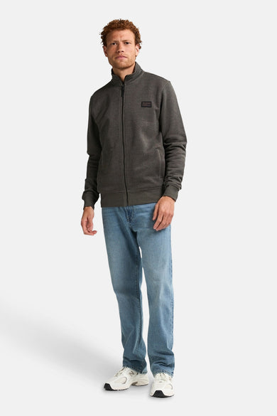 Gilet de kaki de Petrol Industries, avec des manches longues et une fermeture éclair, porté avec un jean bleu et des baskets blanches.