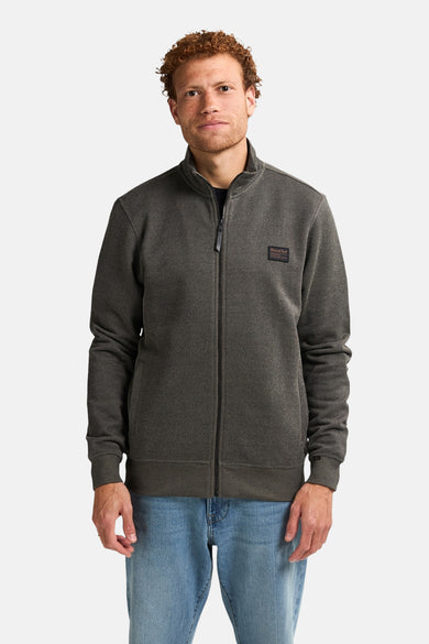 Gilet kaki de Petrol Industries, avec fermeture à glissière et jeans bleus.