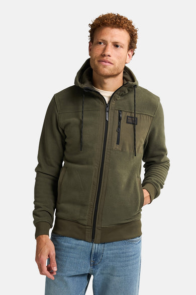 Groene sweater gilet van Petrol Industries met capuchon en een ritssluiting, gecombineerd met blauwe jeans.