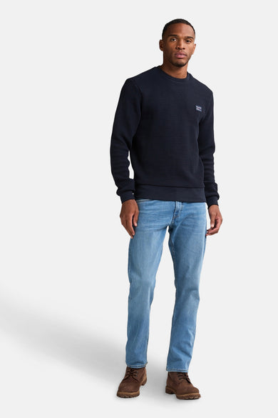 Blauwe trui met ronde hals van Petrol Industries®, met een subtiele textuur en gecombineerd met jeans en bruine schoenen.
