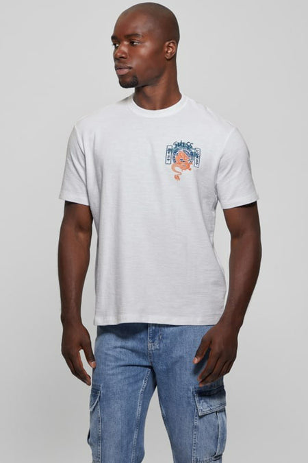 T-shirt blanc à manches courtes Guess® avec imprimé dragon graphique et détails bleus, porté par un homme.