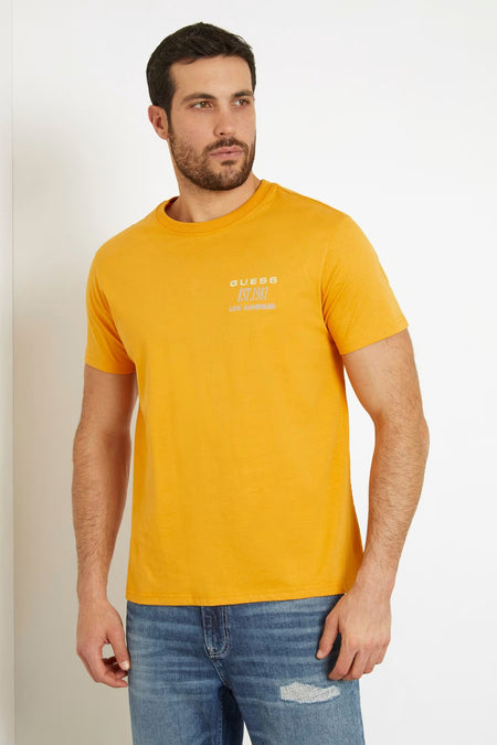 T-shirt orange de Guess avec des manches courtes et un petit logo, porté avec un jean bleu.