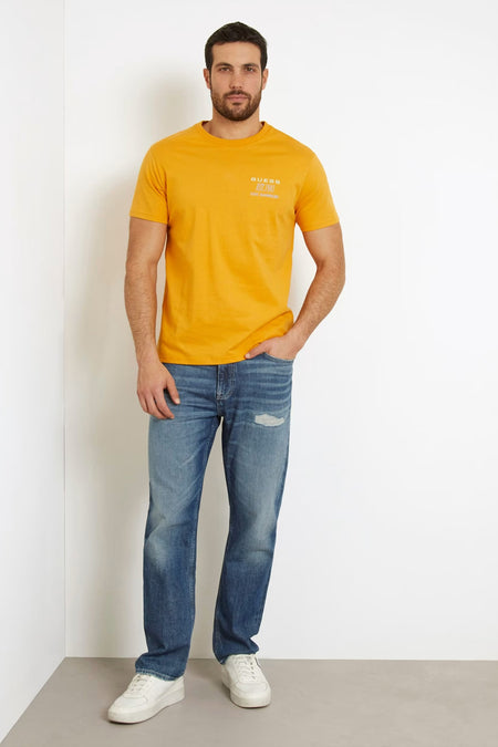 Oranje T-shirt met korte mouwen van Guess, gedragen met blauwe jeans en witte sneakers.