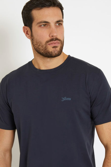 T-shirt bleu à manches courtes de Guess, couleur unie et logo sur la poitrine.