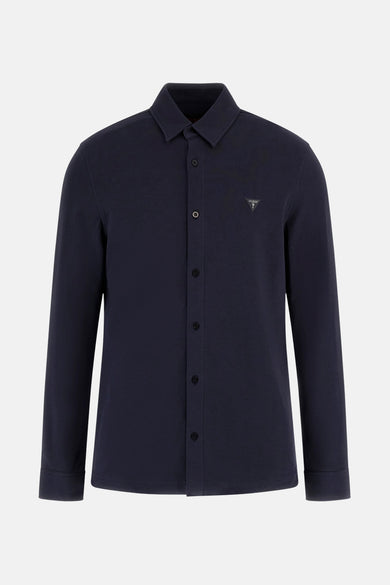 Chemise bleue à manches longues de Guess, avec des coutures subtiles et une fermeture à boutons sur les poignets.