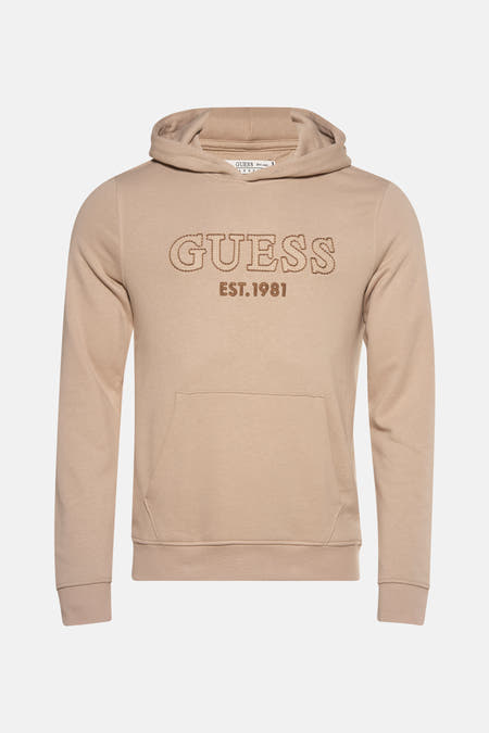 Beige sweater met kap van Guess met een logo en “EST.1981” erop.