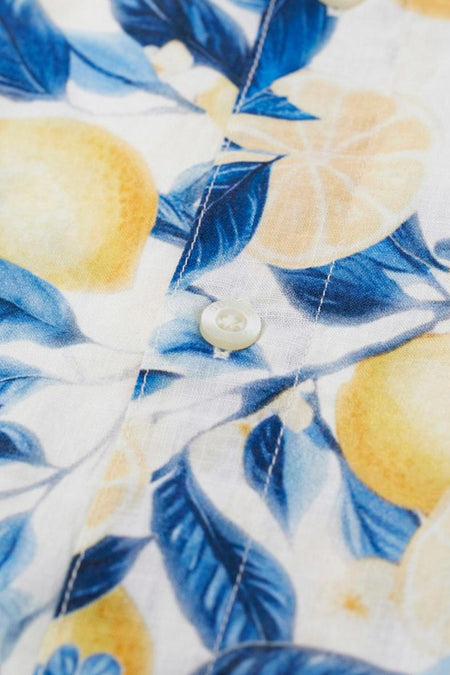 Chemise blanche à manches courtes Guess, avec motif de feuilles bleues et citrons jaunes et un bouton.