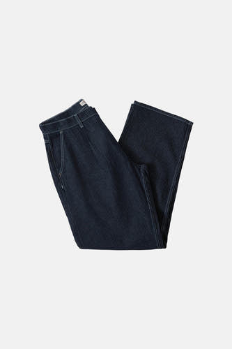 Jean large de denim bleu foncé de Guess, avec des surpiqures blanches et porté avec une ceinture noire.