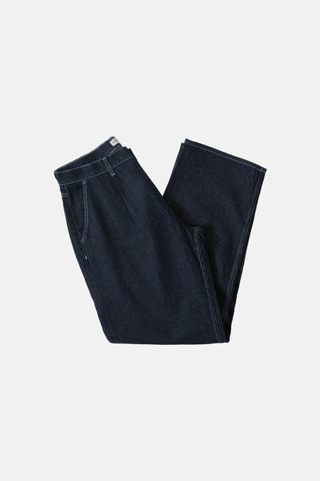 Jean large de denim bleu foncé de Guess, avec des surpiqures blanches et porté avec une ceinture noire.