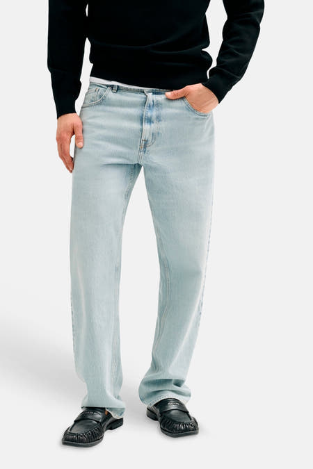 Lichtblauwe straight jeans van Guess, gedragen door een model met een zwarte trui en zwarte loafers.