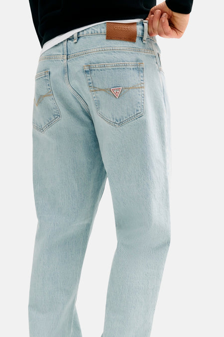 Rechte lichtblauwe spijkerbroek van Guess met leren taillebandpatch en driehoekig logo op de achterzak, achteraanzicht.
