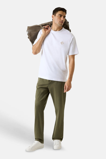 Groene broek van Guess met losse pasvorm, gedragen door een man met wit T-shirt en witte sneakers.