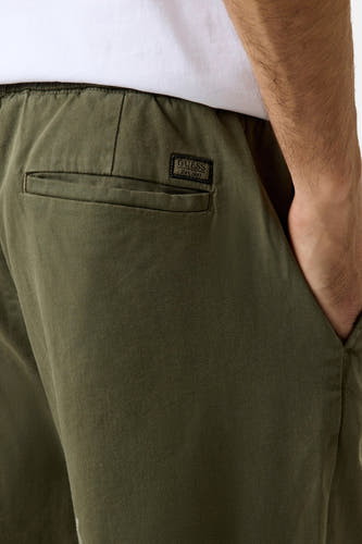 Pantalon vert Guess avec taille élastique, poche arrière avec écusson logo noir et poche pour les mains.