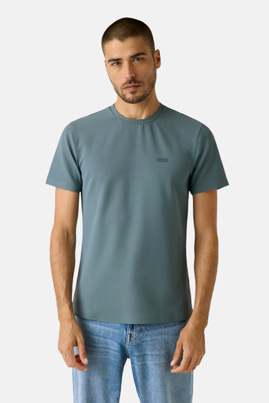 Blauw T-shirt met korte mouwen van Guess, met een kleine print op de borst en gedragen met een jeans.

