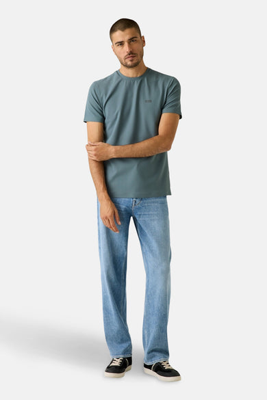 Blauw T-shirt met korte mouwen van Guess, gedragen met een losse jeans en zwarte sneakers.
