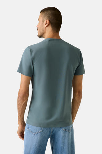 T-shirt bleu à manches courtes de Guess, vu de derrière, porté avec un jean.