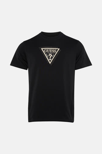 T-shirt noir de Guess, avec un imprimé graphique sur la poitrine, porté avec un jean déchiré et des baskets.
