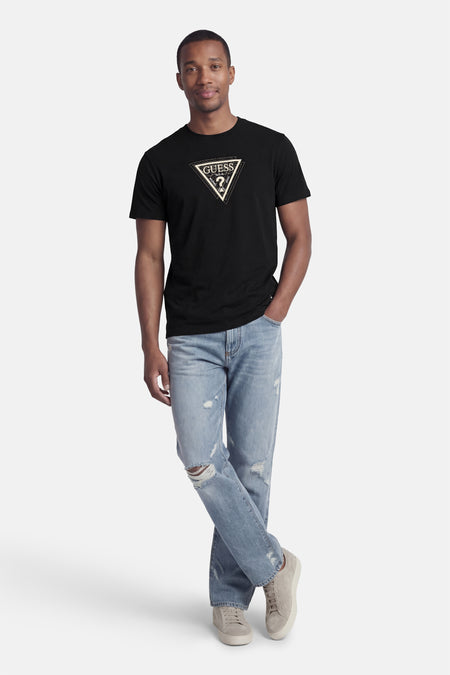 Zwart T-shirt van Guess, met een grafische print op de borst, gedragen met een gescheurde jeans en sneakers.
