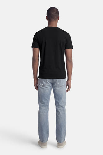 T-shirt noir Guess®, à manches courtes, porté avec un jean bleu et des chaussures grises, vu de dos.